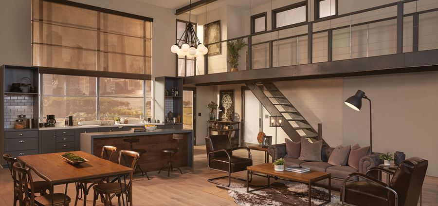 A well-lit rustic loft at dusk. There is a kitchen area, dining table, couch and chairs.