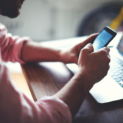 person using a smartphone by an open laptop