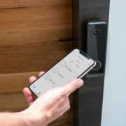 A smartphone is being held by an access control reader to open a door.