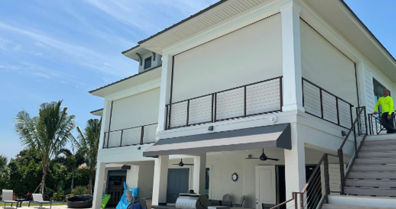 Image is of a hurricane-strength motorized screen on all sides of a home’s exterior.